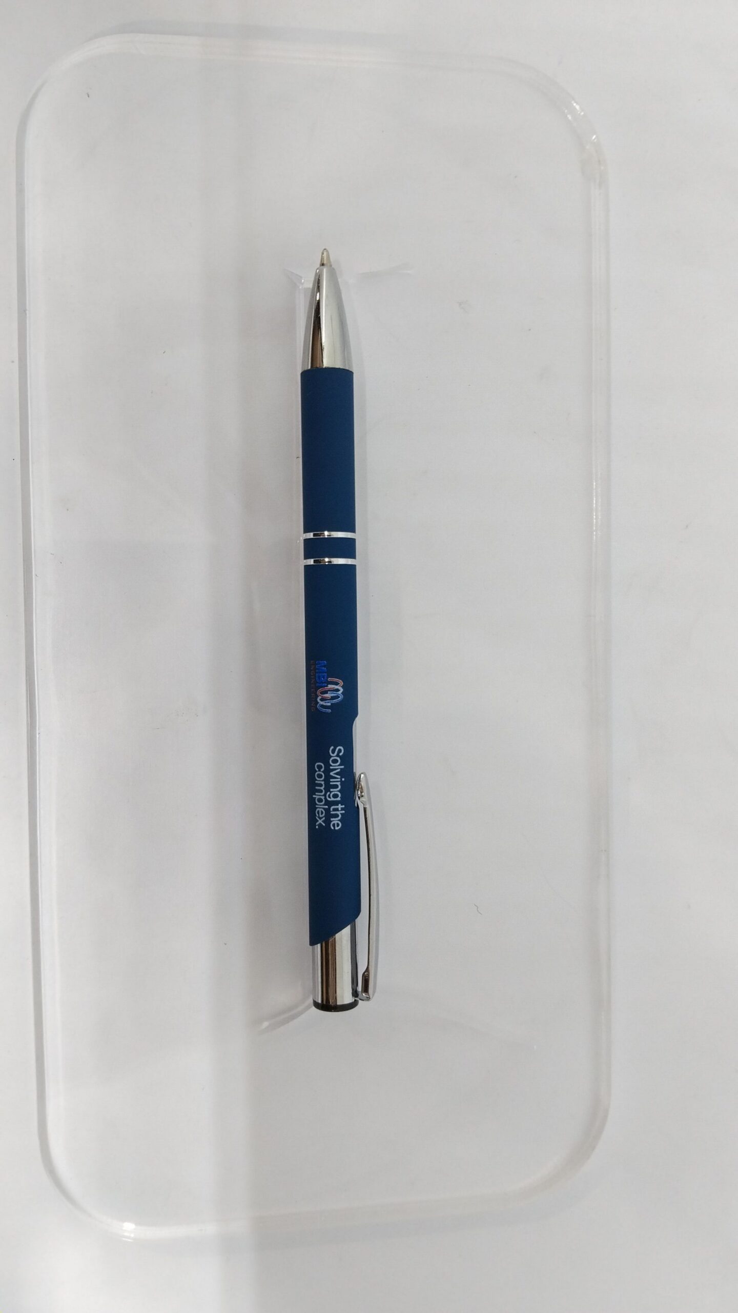 A blue and silver MBI Engineering pen on a clear, rectangular tray with a white background.