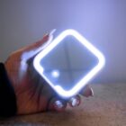 A hand holding a glowing, square-shaped LED night light with rounded corners.