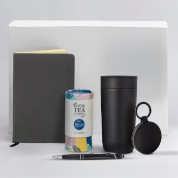 A notebook, tea tin, black tumbler, round keychain, and pen on a white background.