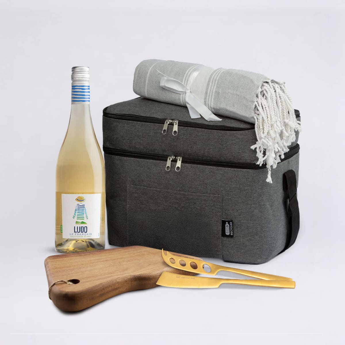 ll8361-202601161422515242381.jpg A wine bottle, cloth, cooler bag, and cheese board with knife on a white background.