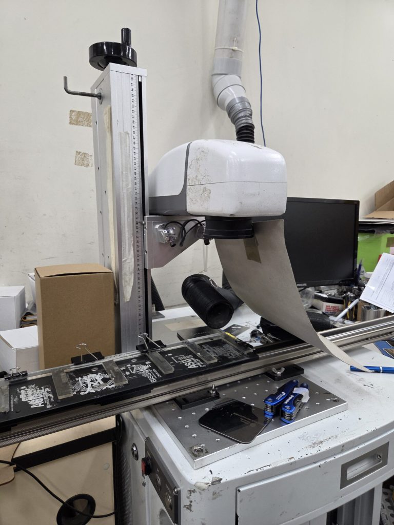 A machine scans slides on a conveyor belt to compare print vs. engraving quality.