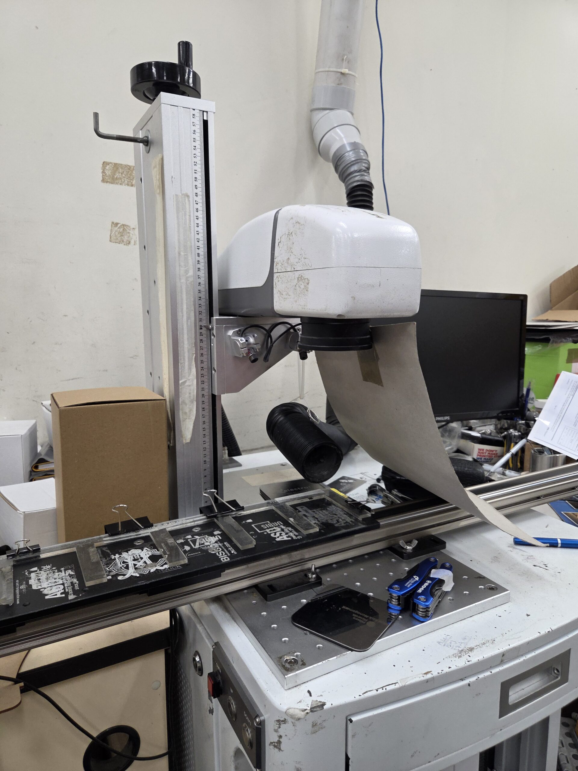 A machine scans slides on a conveyor belt to compare print vs. engraving quality.