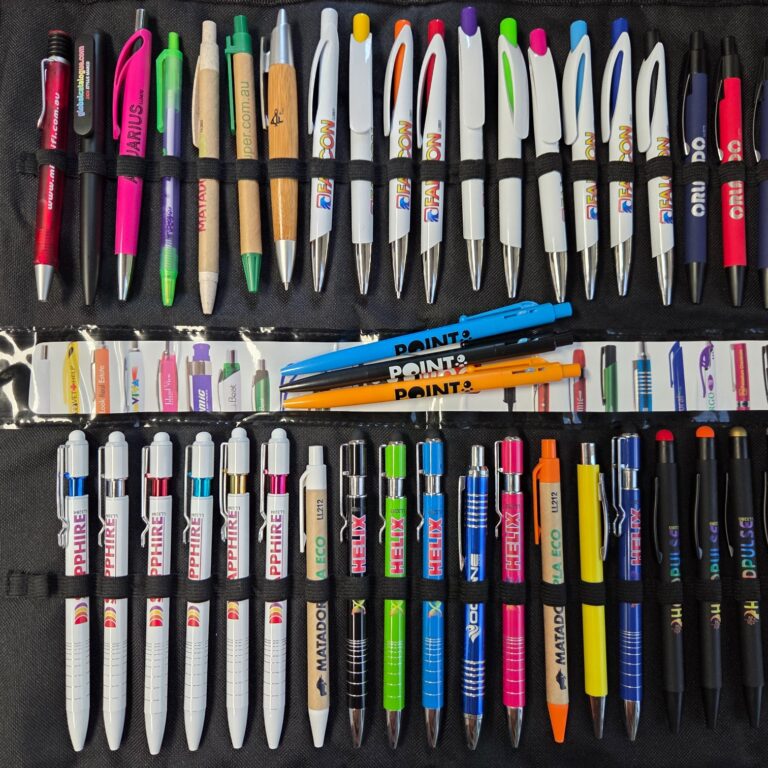 Assorted colorful pens, top promotional items 2025, arranged in rows on a black background.