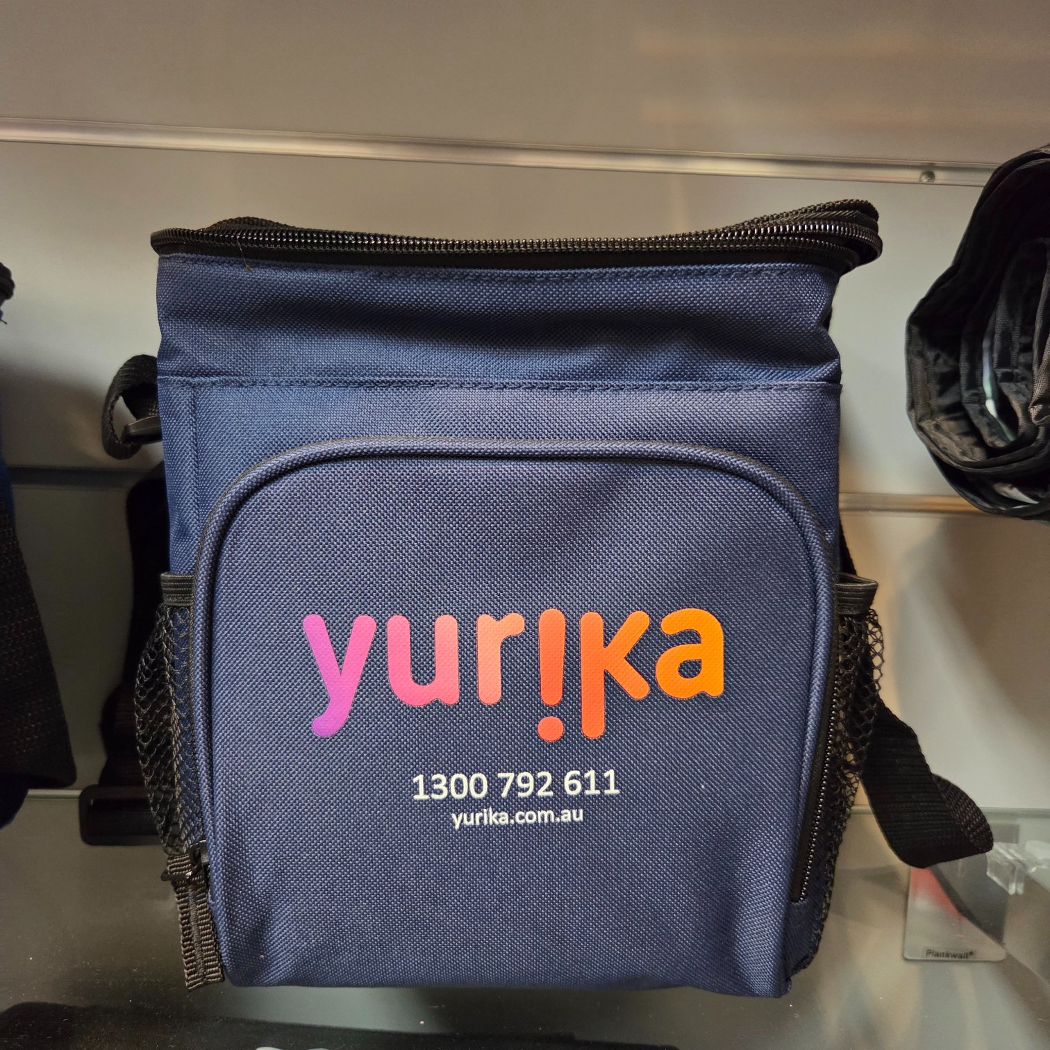 A navy blue bag with yurika and contact info, offering quality products in vibrant letters.