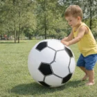 Toddler in a park pushes a large Soccer Shape BeachBalls on green grass.