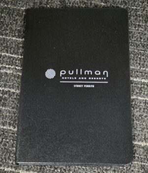 Black folder with Pullman Hotels logo on gray carpet, perfect for client advice or product comparison.