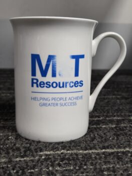White mug with M&T Resources and the slogan HELPING PEOPLE ACHIEVE GREATER SUCCESS in blue text.