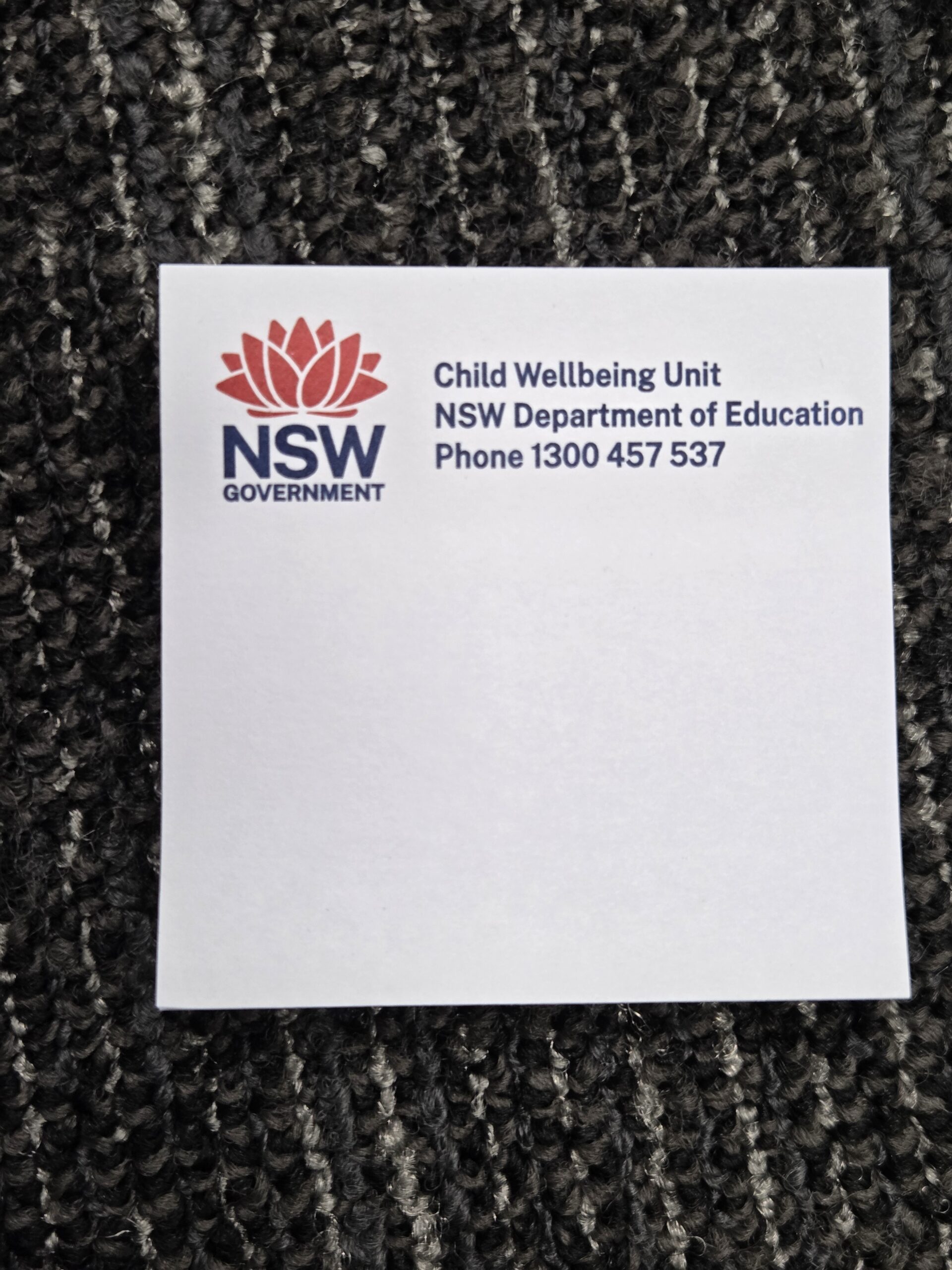 Sticky note with NSW Government logo, helpful for event clean-up or large gatherings, on carpet.