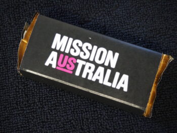 A black box labeled MISSION AUSTRALIA with US in pink, ideal for product comparison.