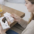 Woman wipes hands with Pocket Tissues at breakfast table.
