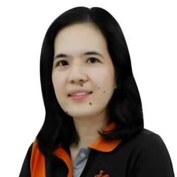 Meet the team: Woman with black hair wearing a black and orange collared shirt, smiling brightly.