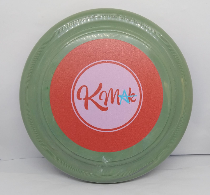 A green frisbee custom branded with a red and pink KMAc logo, inspired by Brisbane’s vibrant Angel Strings.