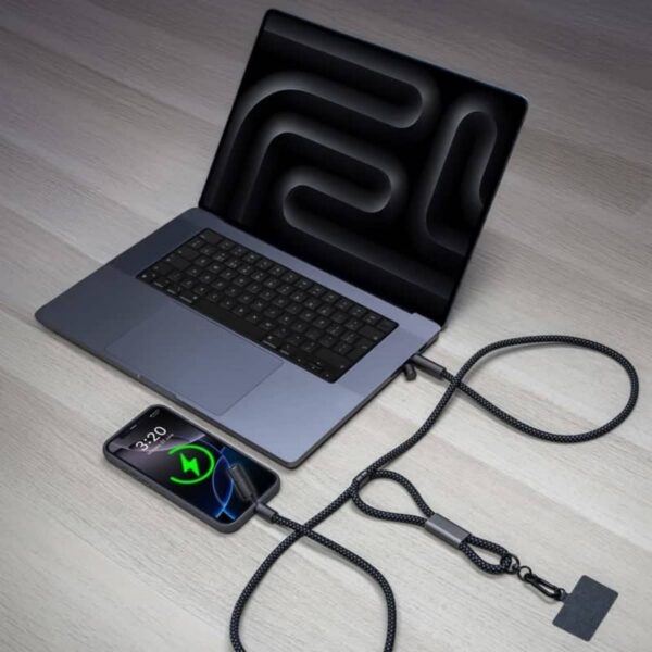 A phone charging from a laptop via a coiled, rope-like cable on a wooden surface.
