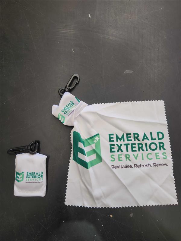 Branded Emerald Exterior Services cloths, ideal for event clean-up, on a dark surface.