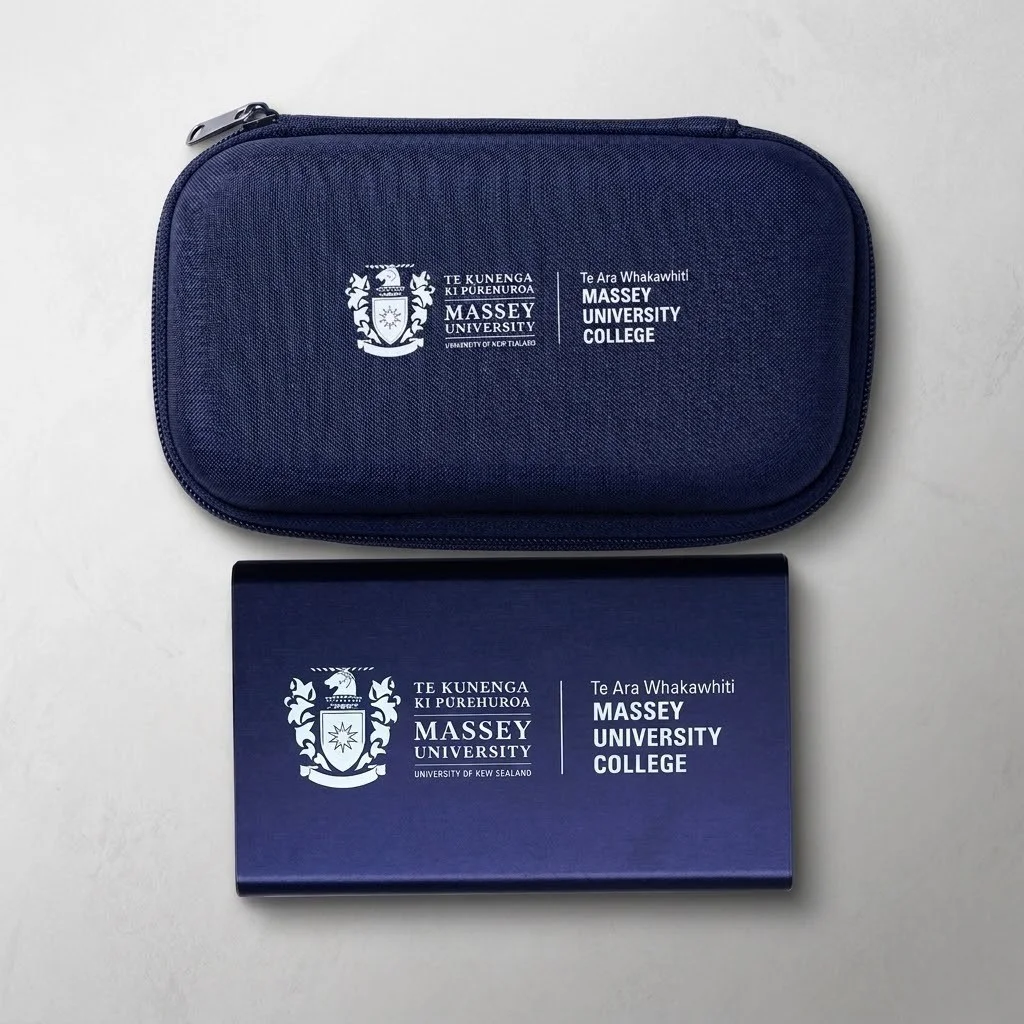 Navy blue Massey University College university merchandise on a light grey surface.