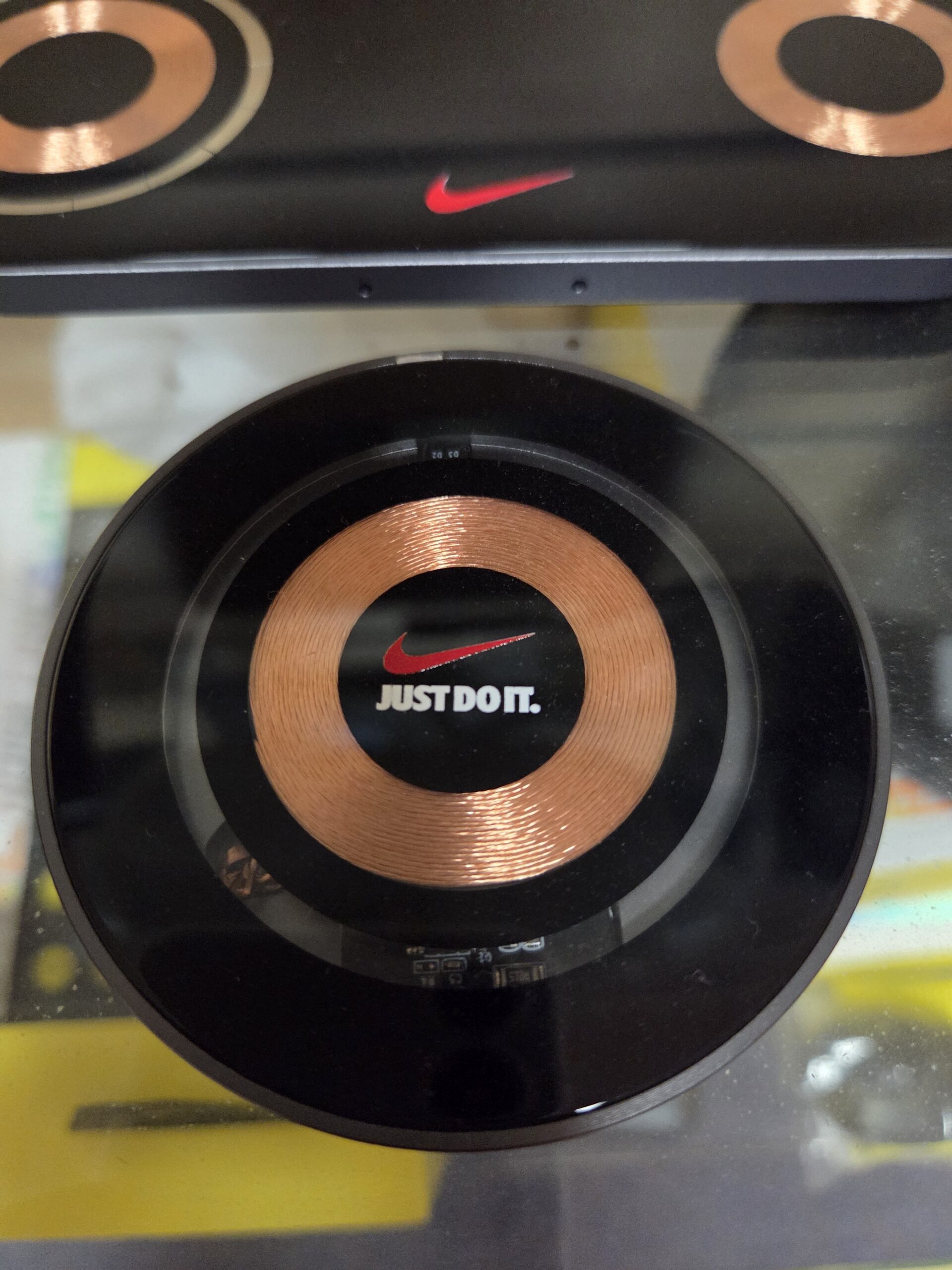 A round Nike Just Do It. wireless charger with reorder products option, copper coil in center.