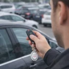 Person holding Amulet Spinning Metal Key Rings near a parked car with an Audi key fob.