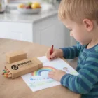 Young child draws a rainbow using Coloured Pencils In Promotional Boxes at a table.