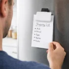 A person uses Fridge Magnet Clips With Branding to hold a shopping list on the fridge.