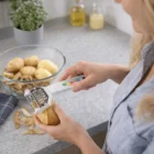 Person peeling a potato with Choppeel Vegetable Peelers in the kitchen.