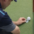 A caddie watches as a man uses Caddie Plastic Golf Ball Markers on the green.