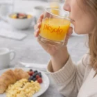 Woman drinks orange juice from Budget 285Ml Everyday Tumblers with breakfast on the table.