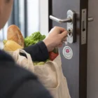 Person unlocks door holding groceries, keys on Kroma Oval Metal Key Rings, bag full.