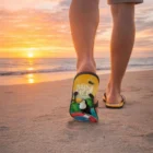 Person walking on the beach at sunset, wearing Flipflop Thongs with SUM HELP text.