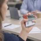 Person holding a Blox House Stress Ball at a desk.