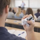 Person holding a Blox Cow Stress Ball in class, facing the lecturer.