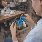 A person uses a Super Customised Lens Cleaner with a penguin and elm wildlife tours logo.