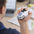Squeezing a Stressballs Vehicle for stress relief at a desk with notebooks and a laptop.