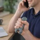 Man on phone holds a Stress Ball Spanner at his desk next to a laptop.