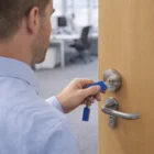 Man unlocks office door with blue key, holding Multipurpose Metal Key Rings on a keychain.
