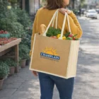 Woman with eco-friendly Yara Jute Tote Bag, CHAMPLAIN BUSINESS SERVICES logo visible.