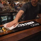 Bartender wipes Matrix Large Counter Mats with a white cloth in a bustling bar.