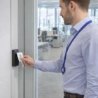 Man uses Triton Lanyards for ID card access at a secure office door with card reader.
