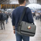Man in a busy train station carrying Conference Bags with Riff Praia Hotel logo.