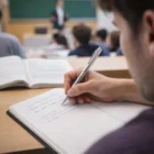 A student takes notes in class with Quax Ball Pens and a notebook.