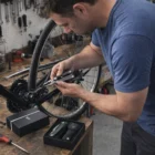 Man repairs bicycle wheel at workbench using Zurich Multi Tools with toolkit nearby.