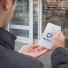 Person uses Kinsan Hand Sanitiser Cards outside store entrance for extra protection.