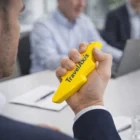 Close-up of a person holding a yellow Lightning Bolt Decorated Stress Toy in an office meeting.