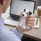 Person squeezing a Puppy Dog Stress Toy at their desk in front of a laptop.