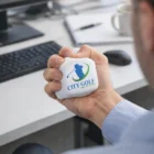 Person squeezing Cube Stress Toys at a desk with a keyboard and mouse.