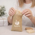 Placing soap into a Sari Jute Gift Bag Small on a table with more soaps nearby.