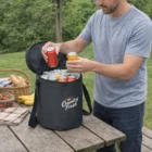 Man with Customised Mega 24 Can Cooler Bag on picnic table with soda cans and food outdoors.
