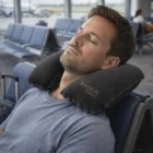Man using the Travel Neck Pillow Custom Gifts in an airport waiting area.