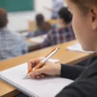 Student writing notes with Branded Thumb Grip Ball Point Pens during a classroom lecture.