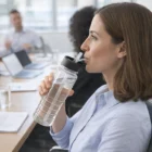 Woman drinks from a Large Drink Bottle - 750 Ml at a conference table in an office.