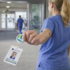 Nurse in blue scrubs shows her ID badge with Retractable Id Holders in a hospital corridor.